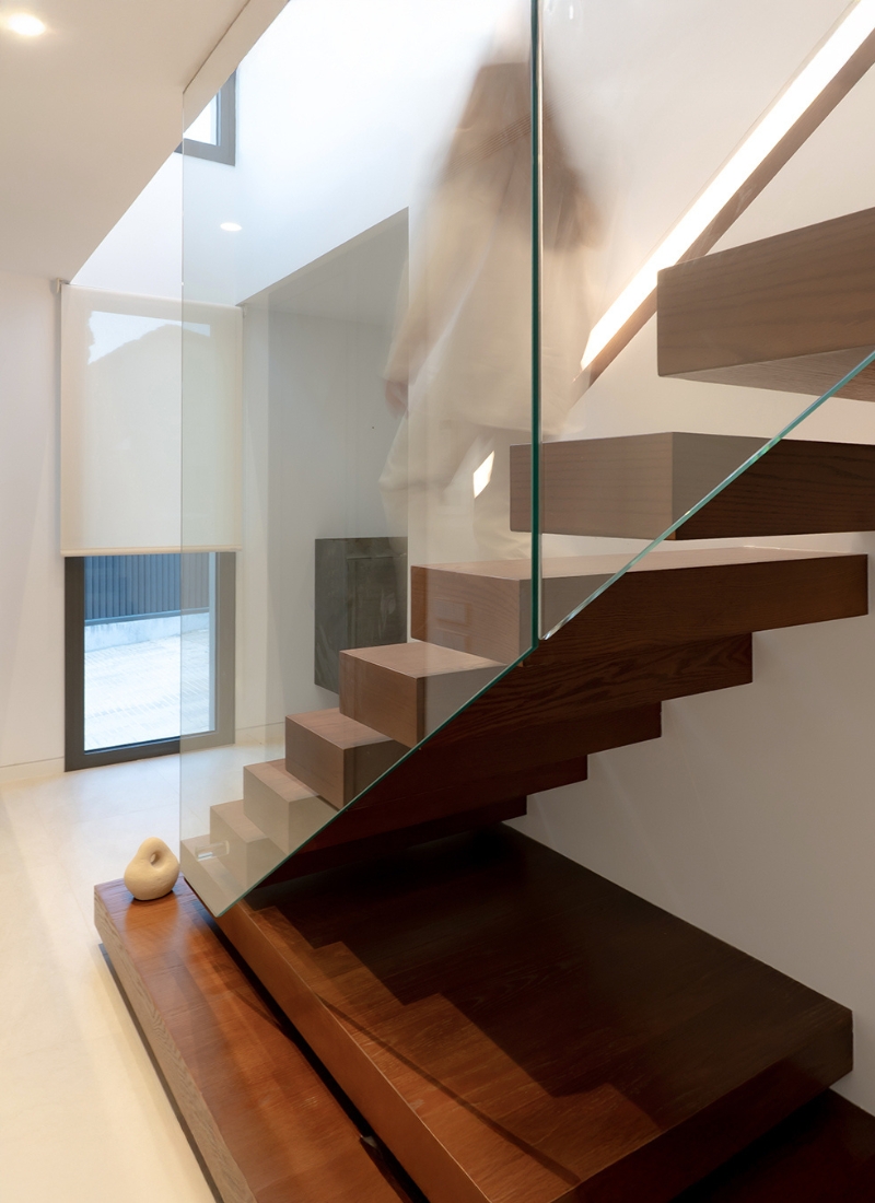 Escalier en bois naturel avec vitrage suspendu en maison modulaire en forme de L