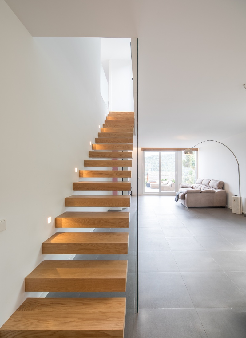 Escalier à marches en porte-à-faux avec rampe en verre surélevée.