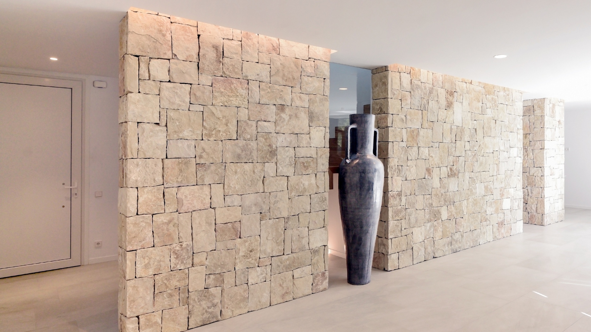 Mur en pierre dans salon ouvert maison préfabriquée en béton