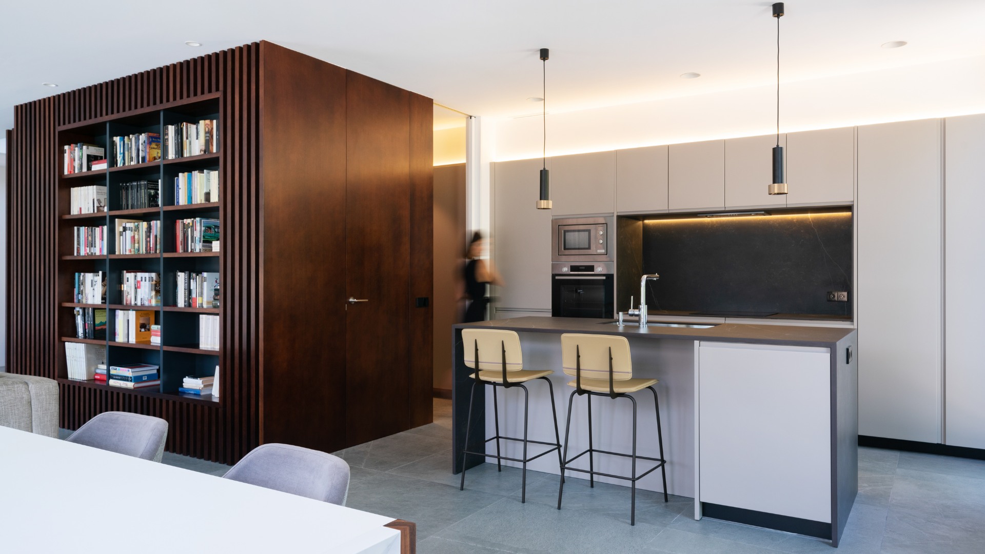 Bibliothèque en bois séparatrice salon cuisine dans une maison modulaire de luxe
