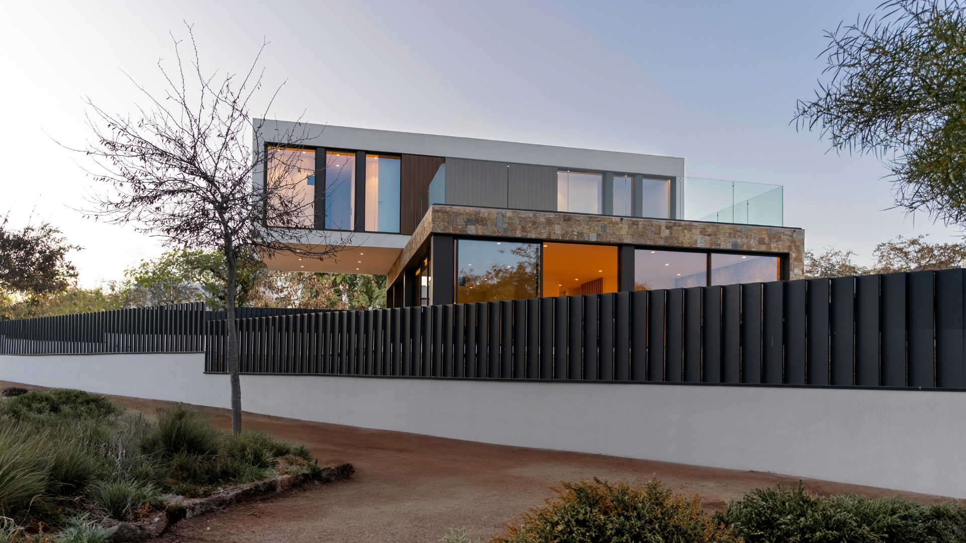 Maison préfabriquée avec avant-toit et façade revêtue de pierre et de bois technologique