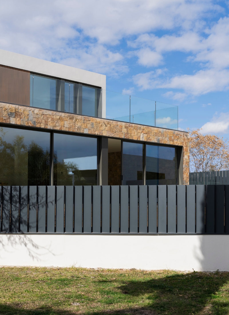 Clôture et revêtement en bois et pierre naturelle de cette maison préfabriquée