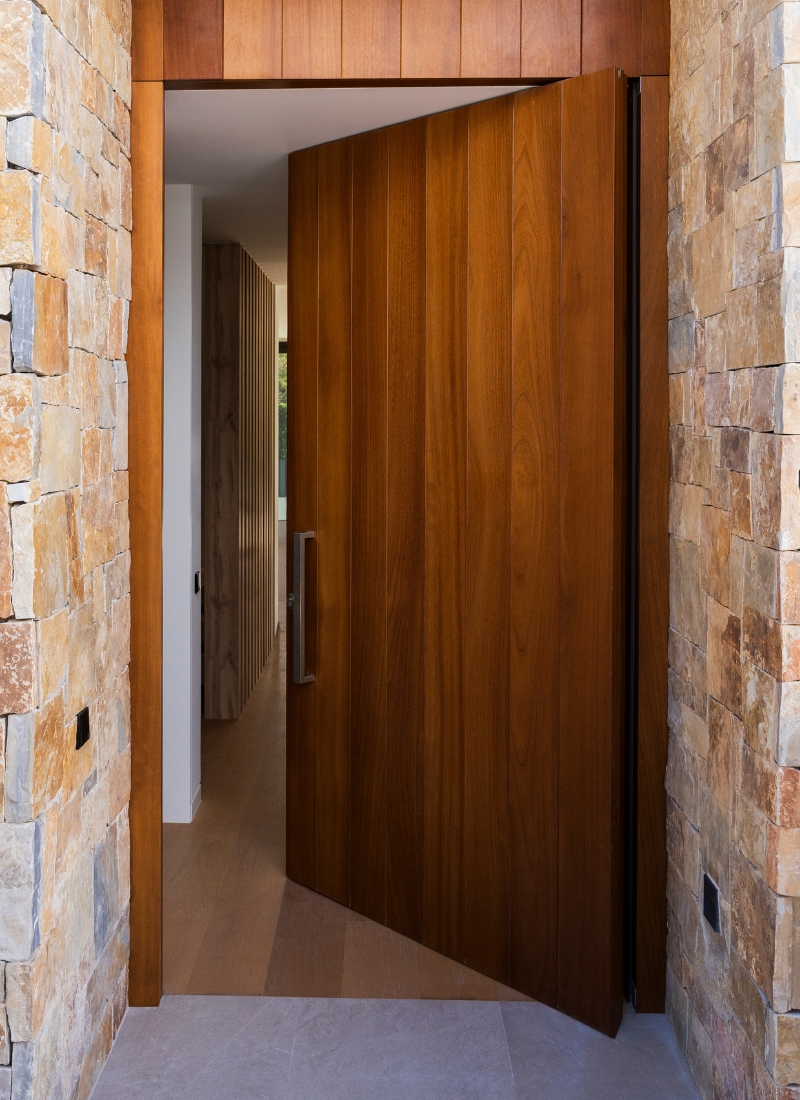 Maison préfabriquée avec porte pivotante en bois et pierre naturelle