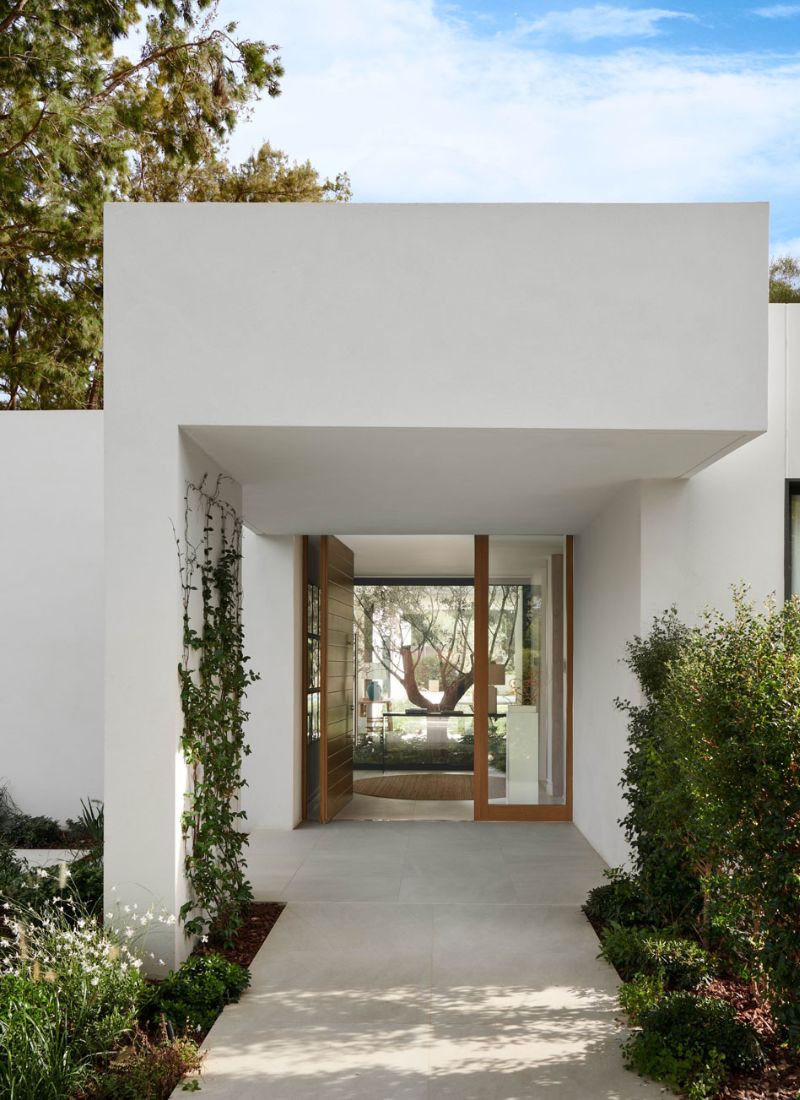 Villa de luxe avec entrée principale à porte pivotante et aménagement paysager arboré